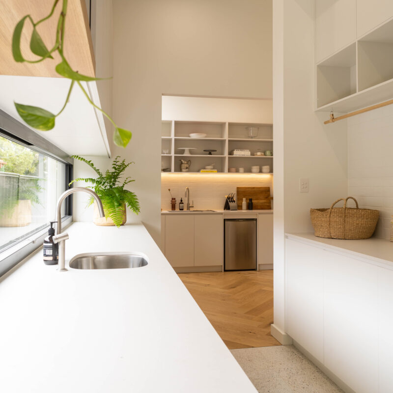 Walk in pantry storage and laundry space all connected together. White, light and bright with warm and natural tones.