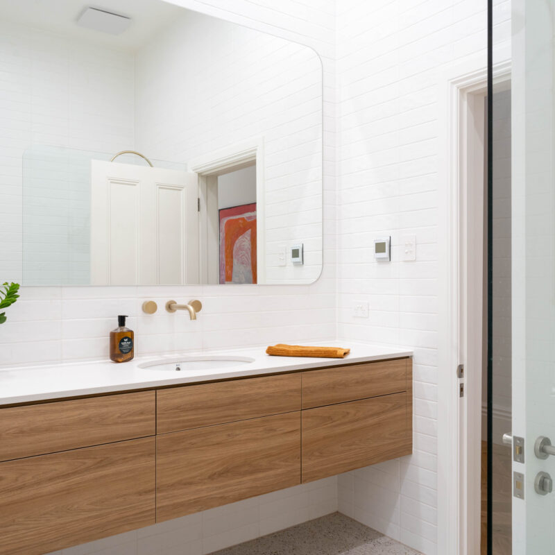 Beautiful bathroom longline drawer vanity in walnut and large rounded corner mirror.