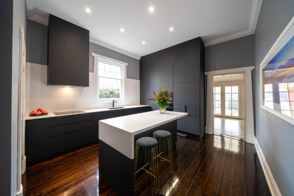 Dark and dramatic. Dark wood floors with black, white and grey tones. Drawer banks, appliance nook, LED strip lighting, black granite sink & tap.