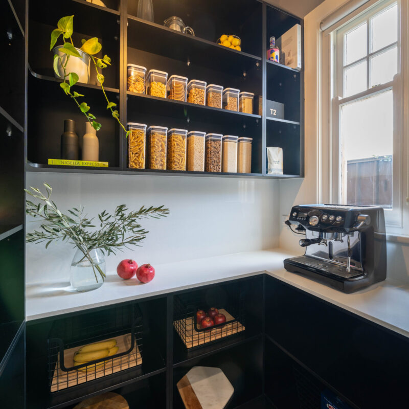Touch Cabinetry. Black walk in pantry with white stone benchtop. L shape with open shelving for storage