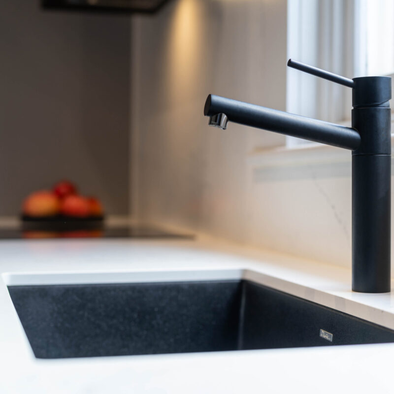 Oliveri Black tap and graphite sink on a white stone benchtop.
