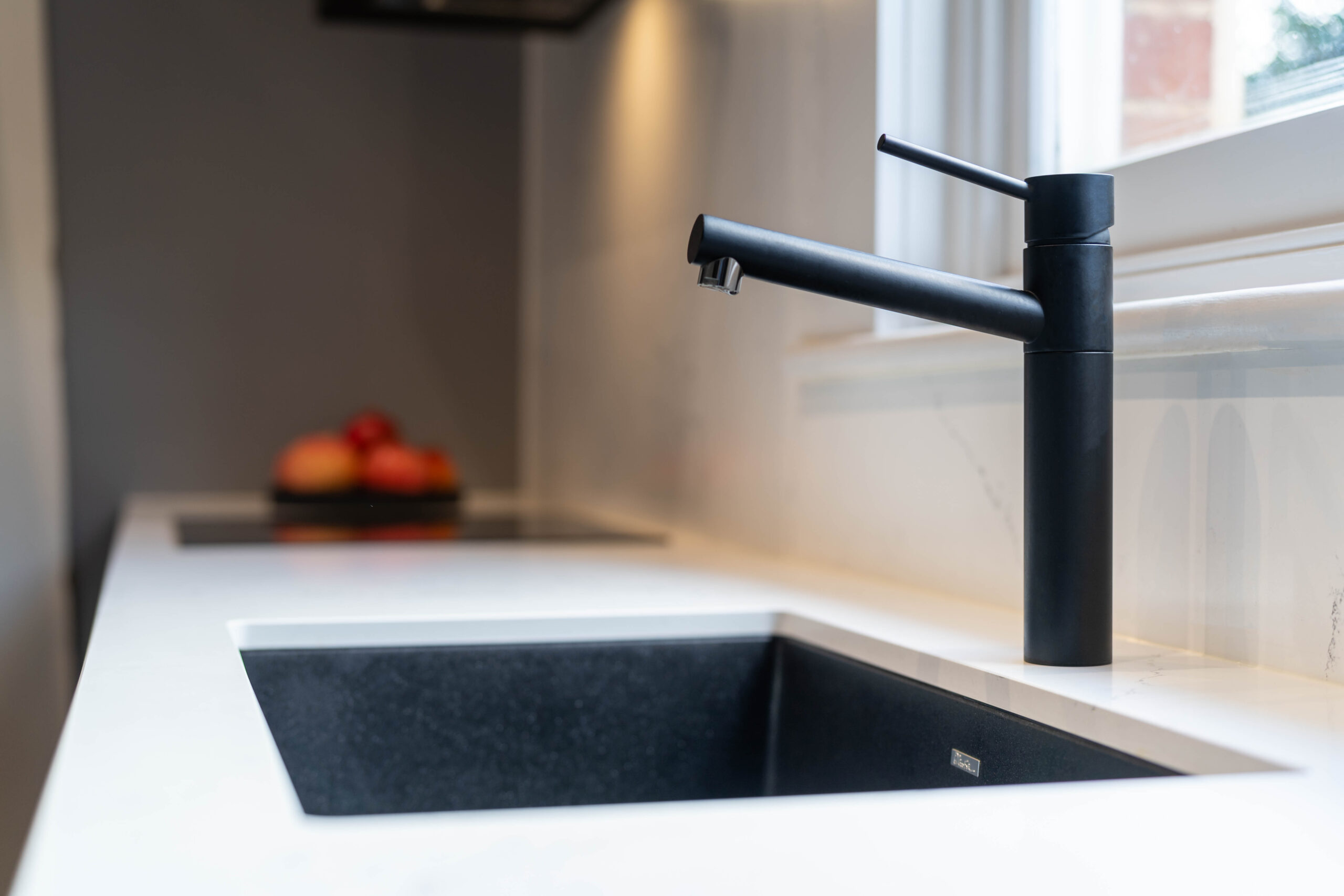 Oliveri Black tap and graphite sink on a white stone benchtop.