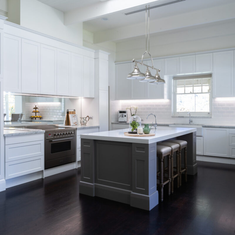 Hamptons style. Farquhar shaker style Barossa profile cabinetry, paired with white beveled edge subway tiles and pendant lighting hanging from the impressively high ceiling above the island all embrace the Hamptons style.