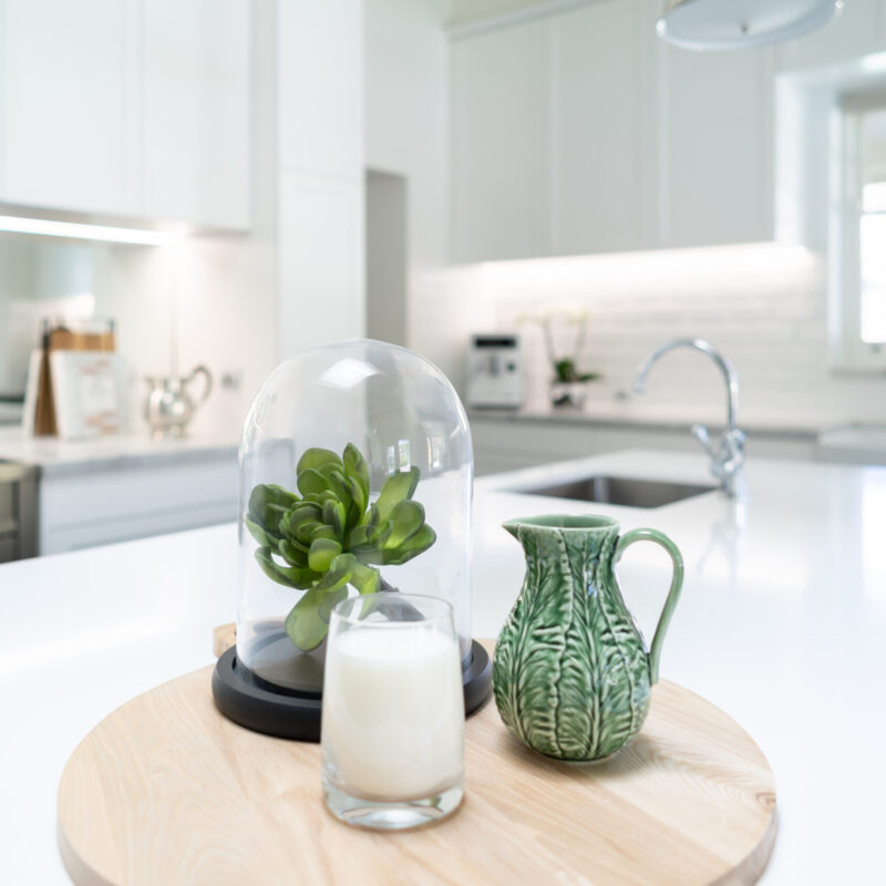 Hampton style kitchen with a decorative display on white stone benchtop.