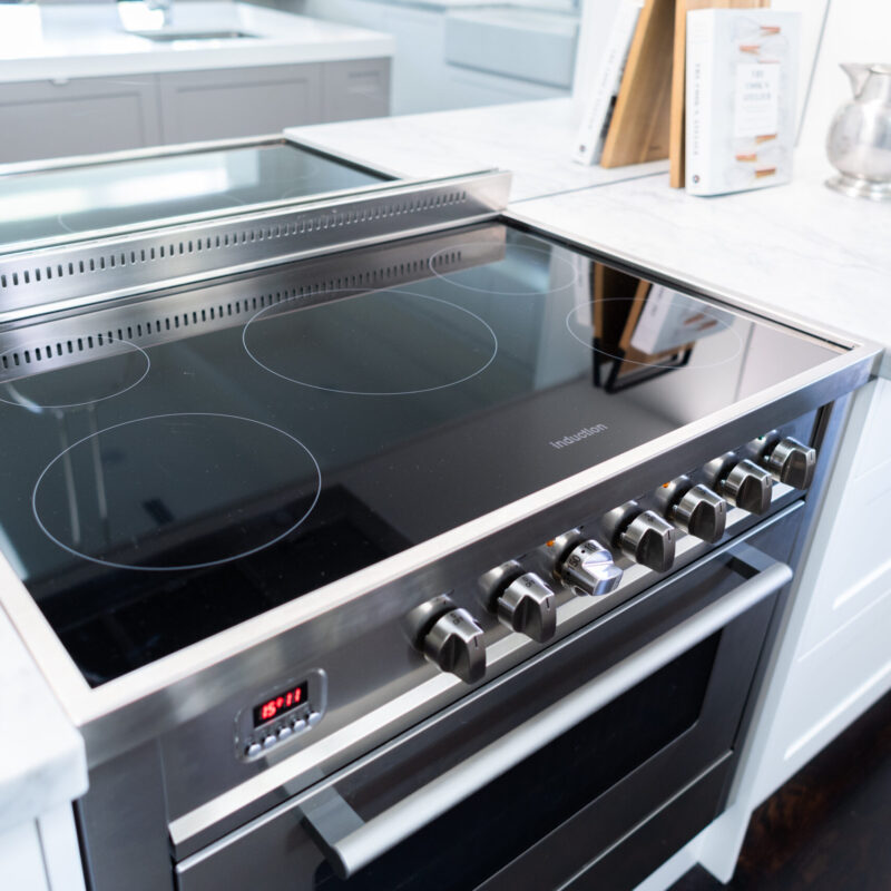 Freestanding Oven in stainless steel highlights the back run of cooking space against a mirrored splashback and white cabinetry.