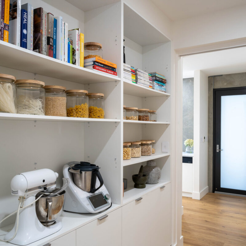 Butlers Pantry. Behind a wall of kitchen cabinetry, uses the same finishes with open shelving to house appliances, cookbooks and everyday staples.