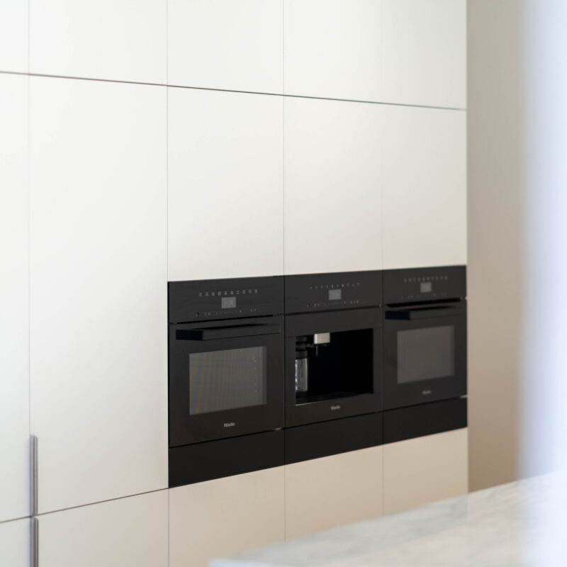 Full height white touch cabinetry housing a run of Black fisher and paykel appliances.
