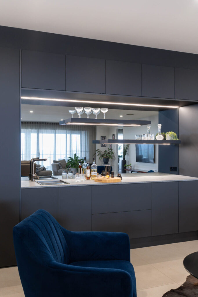 Modern home bar for entertaining. Clean simple lines in Touch supermatte black cabinetry. Mirrored, with shelves and led lights, wine racks and fridge space.