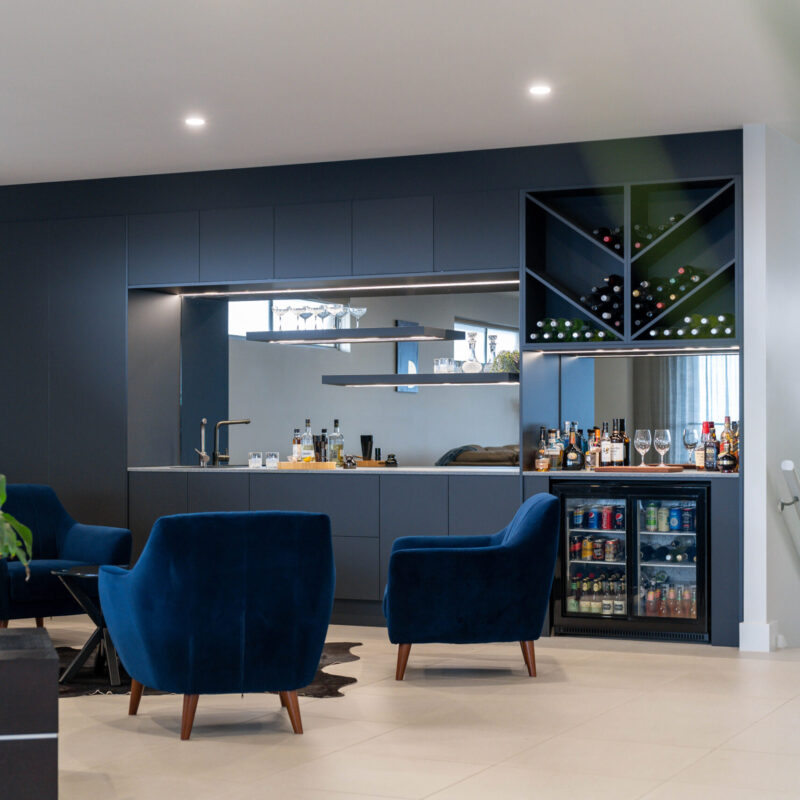 The modern home bar is a design of simple, clean lines, in TOUCH™ super matte black cabinetry. It demands attention, dark and luxurious, in contrast to the greater room filled with natural light and space.