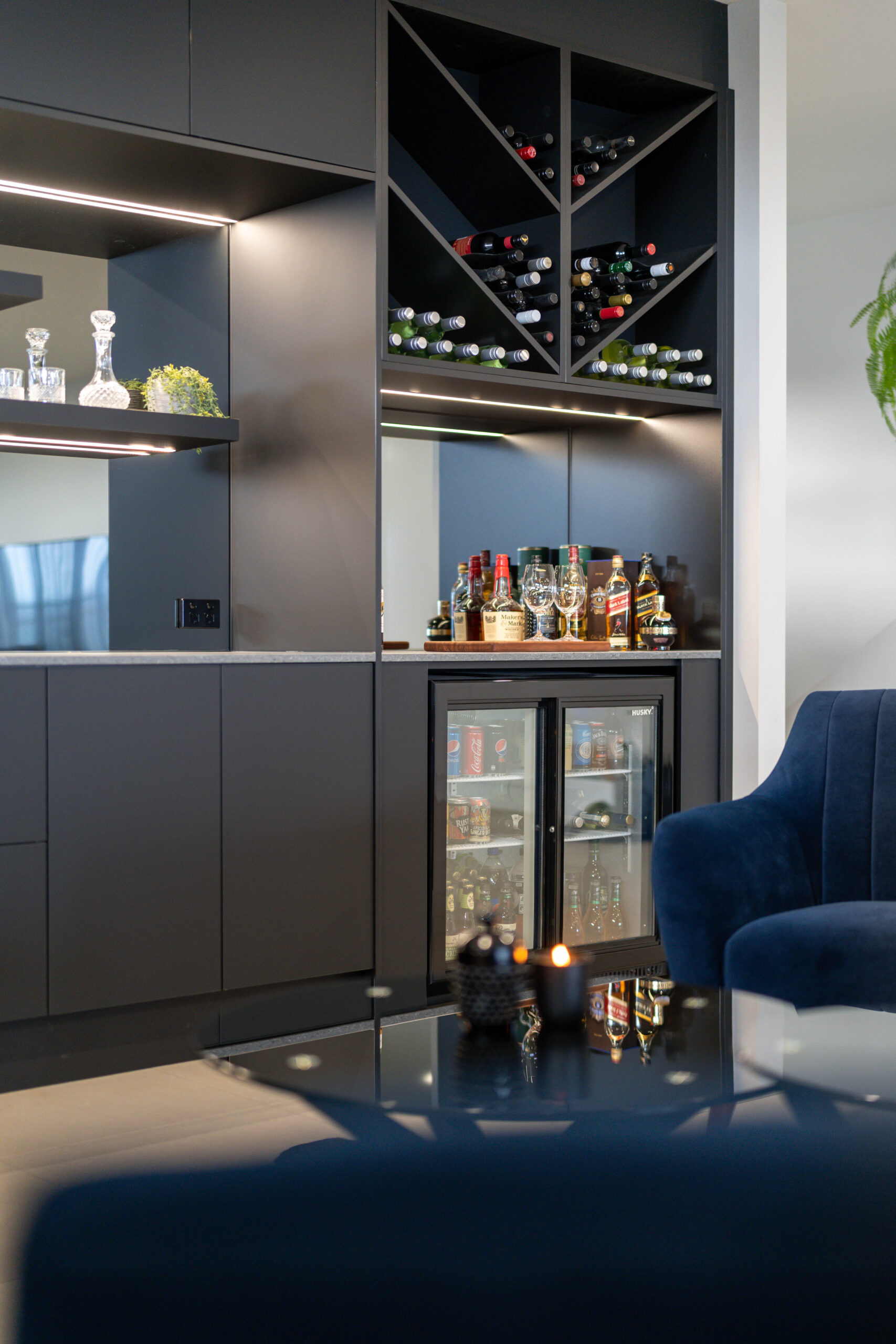 Entertainers bar in black touch cabinetry, wine racks and bar fridge with bottle storage.
