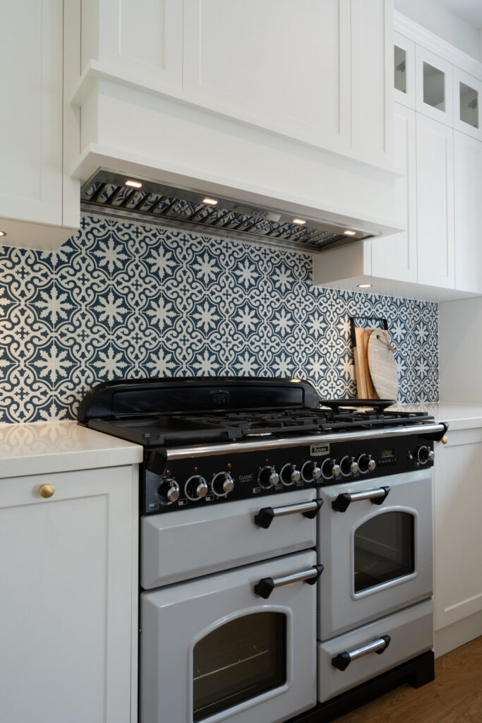 Designer Oven and stove top freestanding with patterned blue and white tiles in a traditional Kitchen space.
