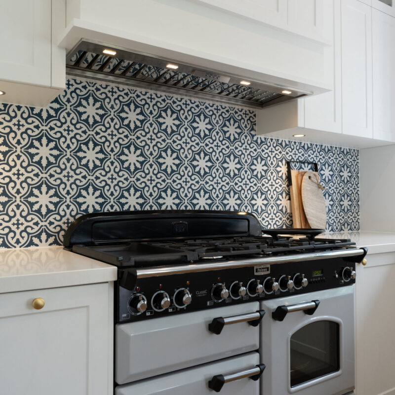 Designer Oven and stove top freestanding with patterned blue and white tiles in a traditional Kitchen space.