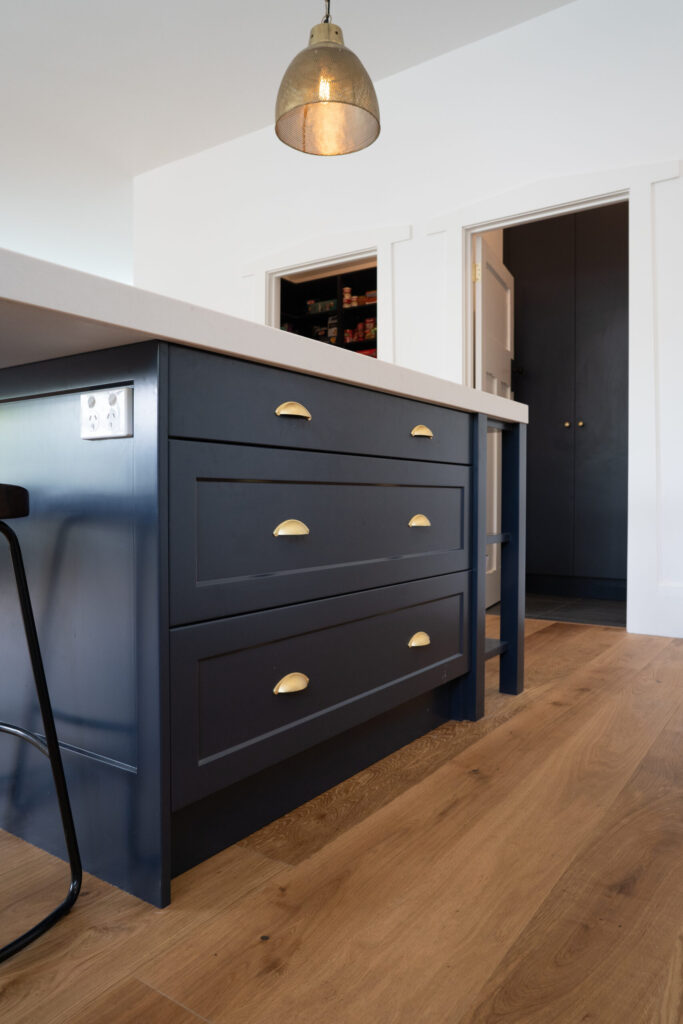 Navy Island bench. Traditional Twist Farquhar Kitchen. gold cup handles and gold pendant light with white stone benchtop.