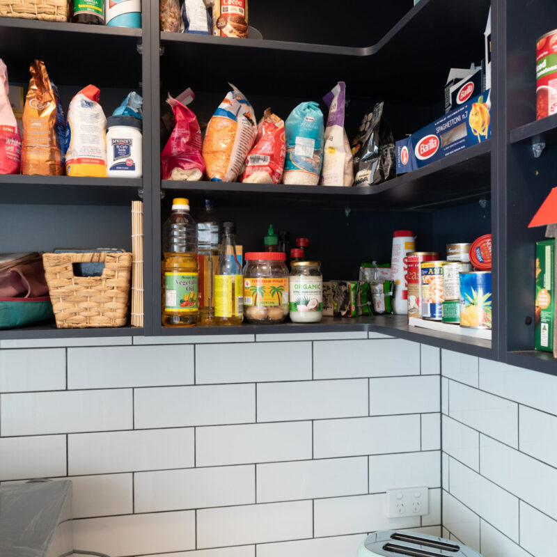 Walk in Pantry. Over head navy open shelving for storage and timber benchtop with open under bench shelving. White gloss subway tiles to match.