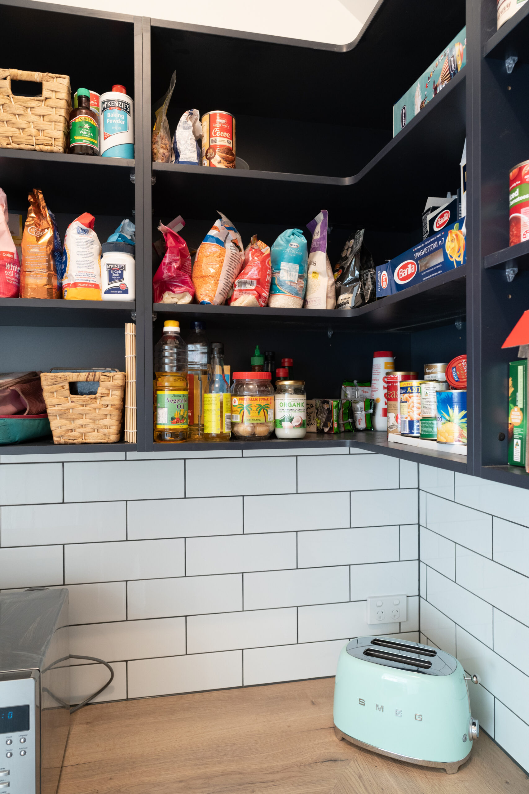 Walk in Pantry. Over head navy open shelving for storage and timber benchtop with open under bench shelving. White gloss subway tiles to match.