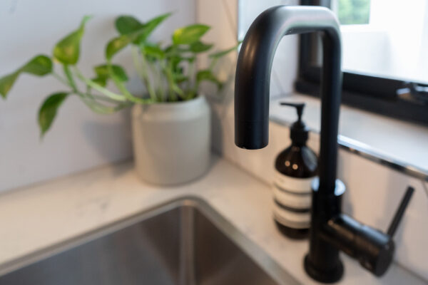 Laundry tub, black tapware and large herringbone gloss tiles.
