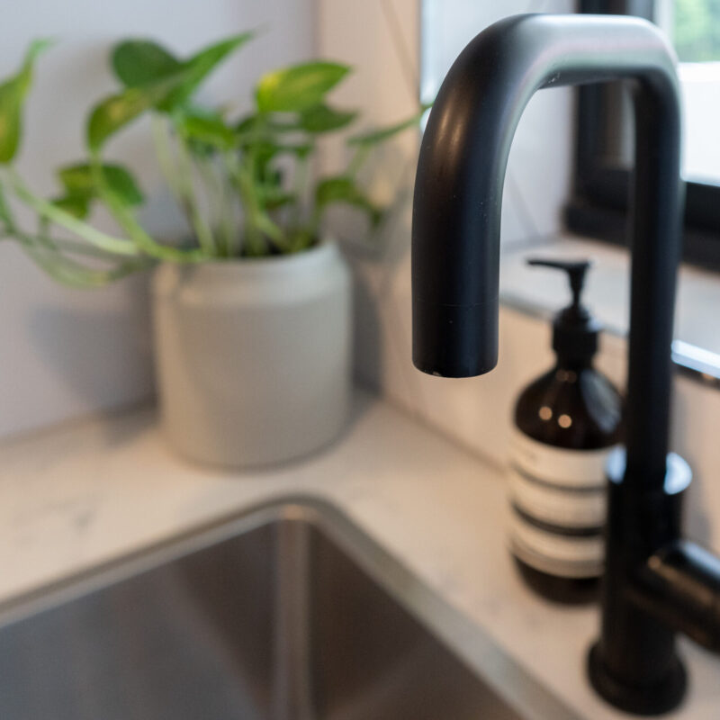 Laundry tub, black tapware and large herringbone gloss tiles.