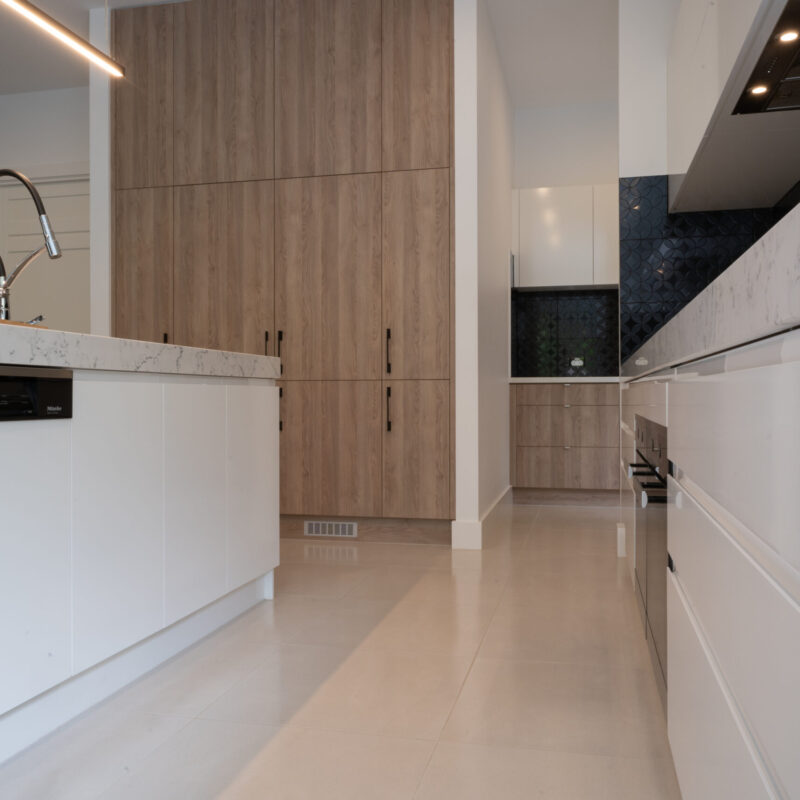 A modern masterpiece kitchen. Thick stone benchtops in grey tones with black, white and timber features.
