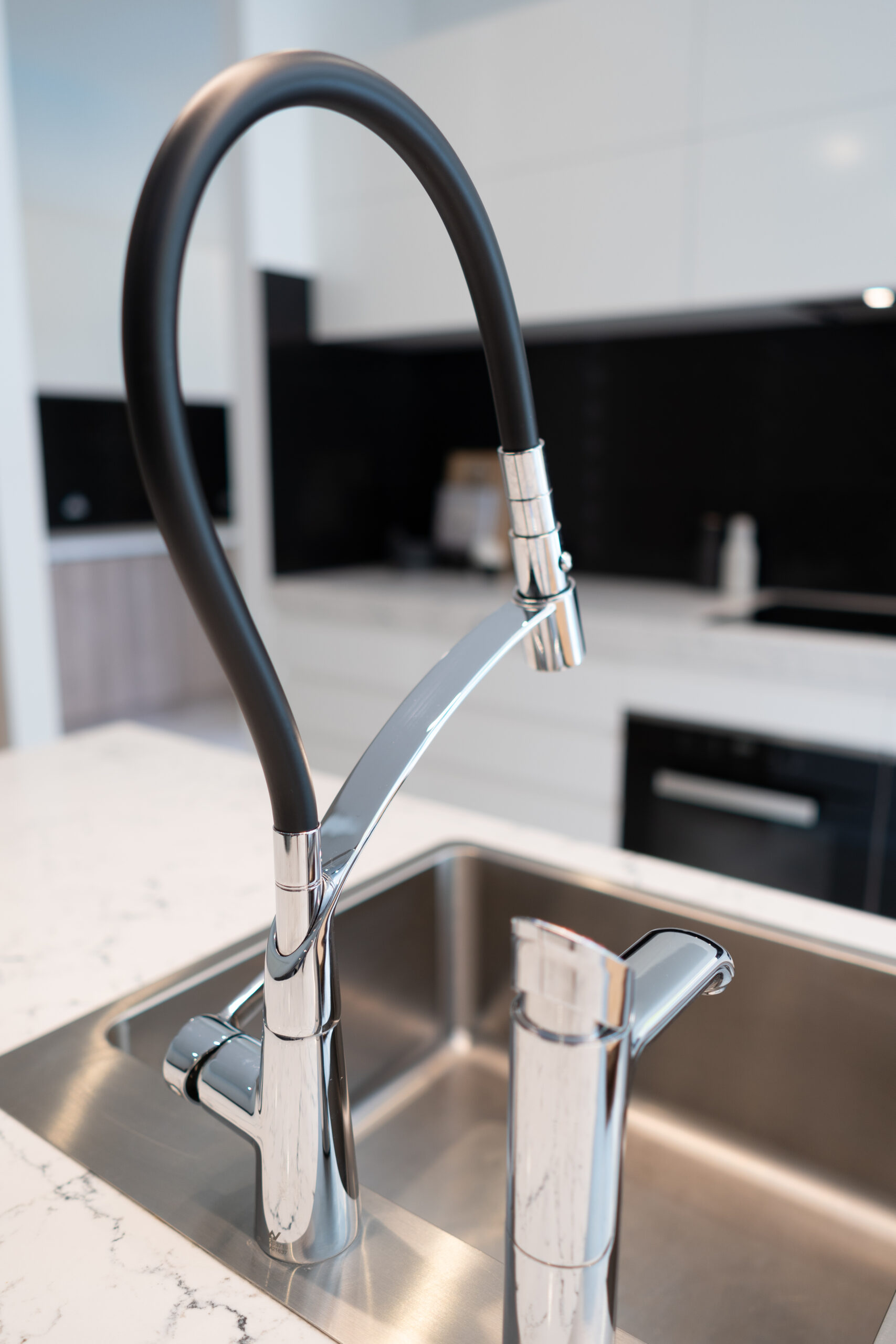 Sink and Tap in kitchen island- Mixer tap black and silver, alongside a zip tap.