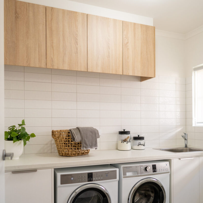 Laundry. Two tone with white and timber. Double space for machines, laminate benchtop and splashback white tiles.