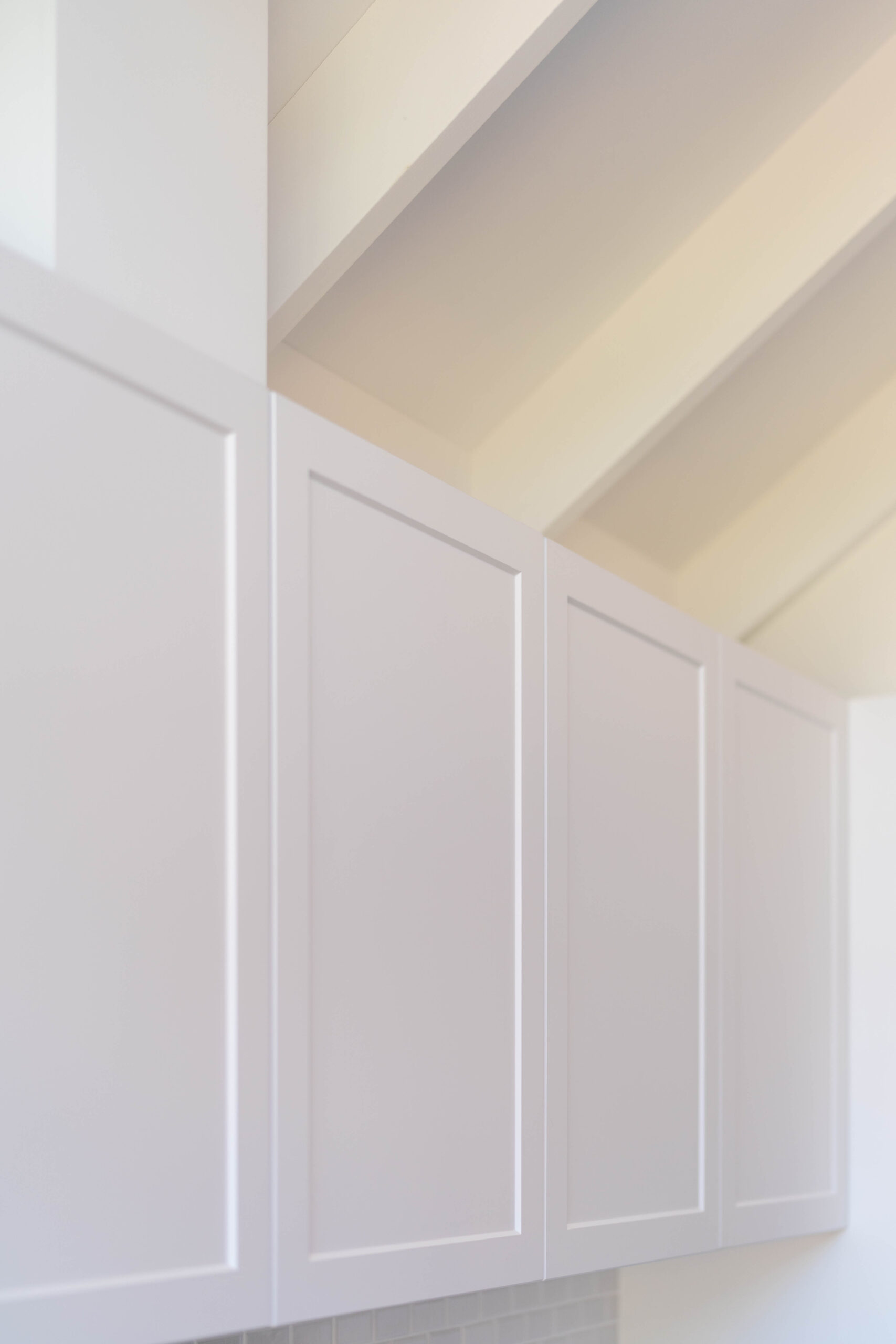 The kitchen is drenched in Farquhar's Premium White cabinetry from top to toe, further illuminating the bright, fresh and open space which has a pitched roof.