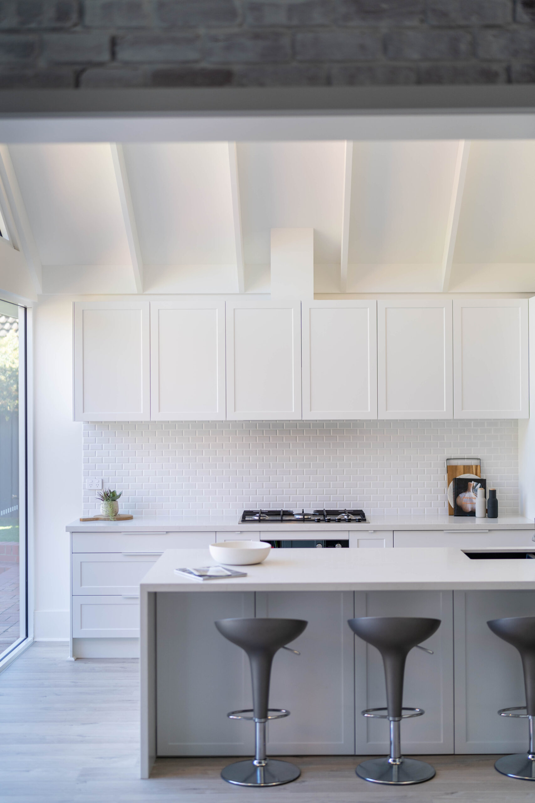 The kitchen is drenched in Farquhar's Premium White cabinetry from top to toe, further illuminating the bright, fresh and open space which has a pitched roof and huge windows allowing an abundance of natural light to flow in.