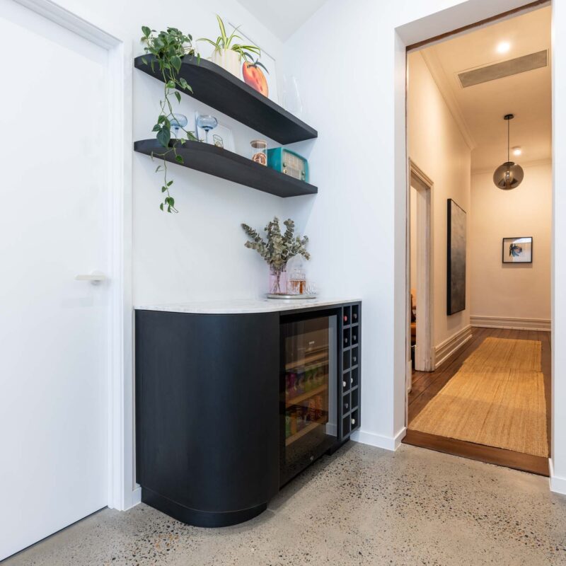 Small bar area featuring black wood grain cabinets and man matching curved ended floating shelves.