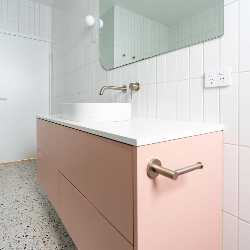 Pastel matte pink vanity with a thin white stone benchtop and white above counter round sink.