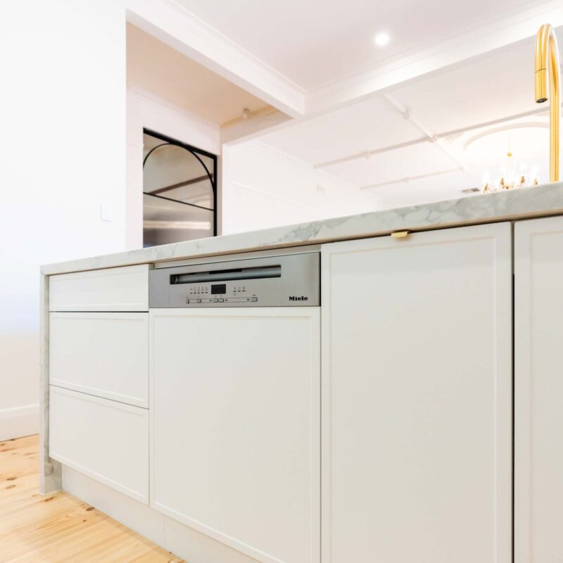 White slim shaker style cabinetry. Includes a semi integrated dishwasher.