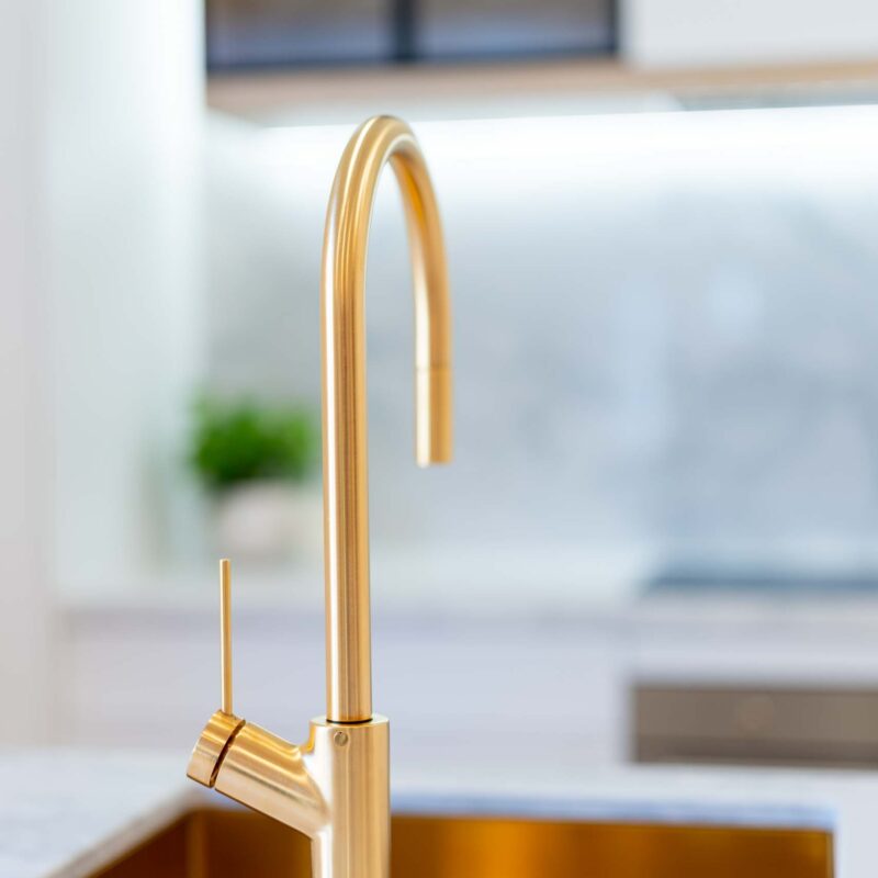 Brushed gold goose neck mixer tap and undermount sink.