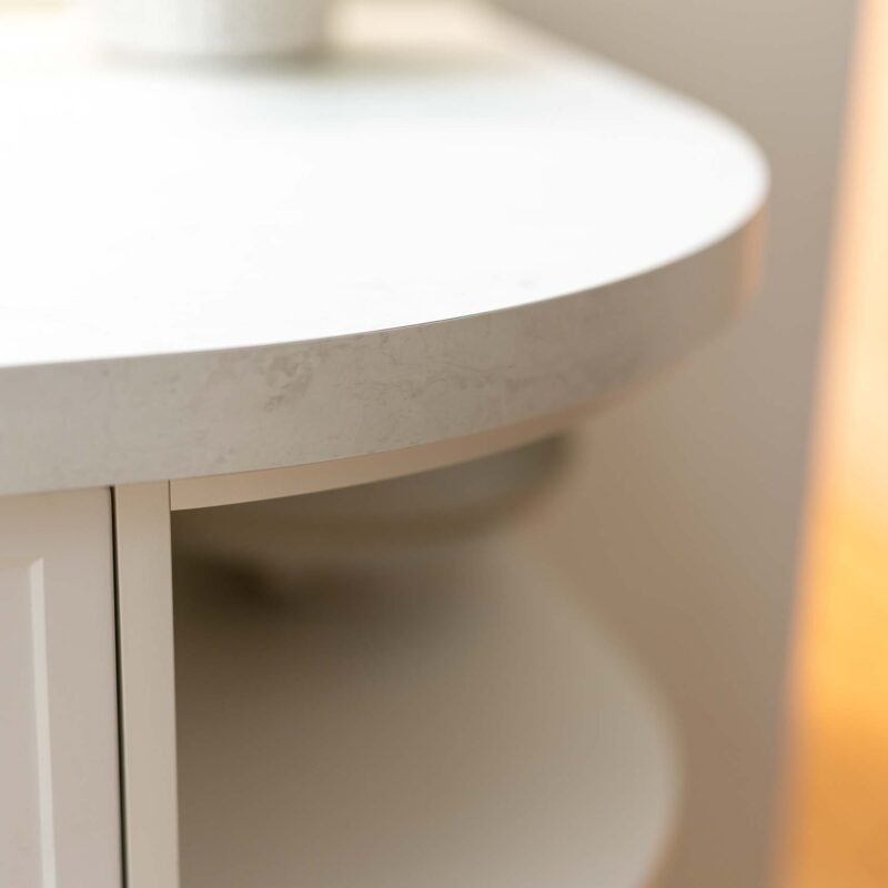 Curved benchtop with matte white curved open shelf below.