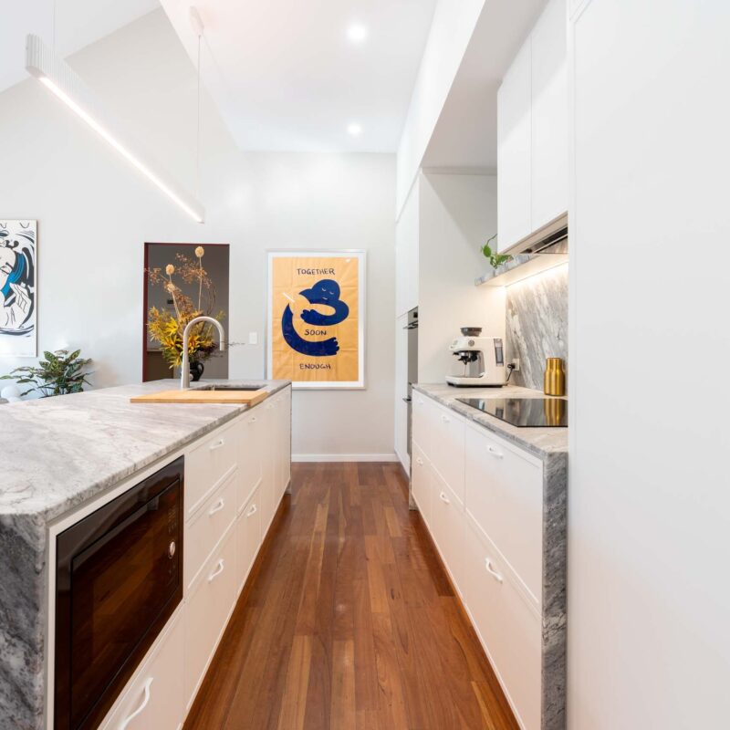Modern kitchen with large island benchtop. White thin shaker profiled cabinets with a bold grey marble benchtop and splashback.