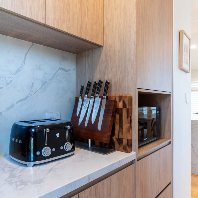 Butlers pantry featuring timber laminate cabinets and light marble benchtops and matching splashback.