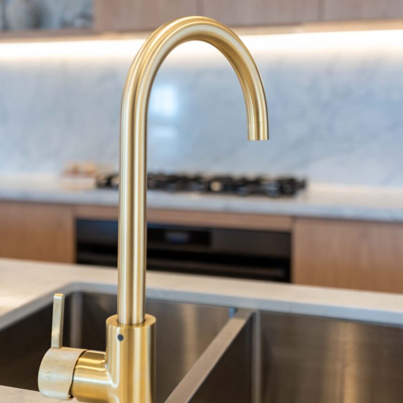 Brushed gold goose neck mixer kitchen tap, and stainless steel under mount double bowl sink.
