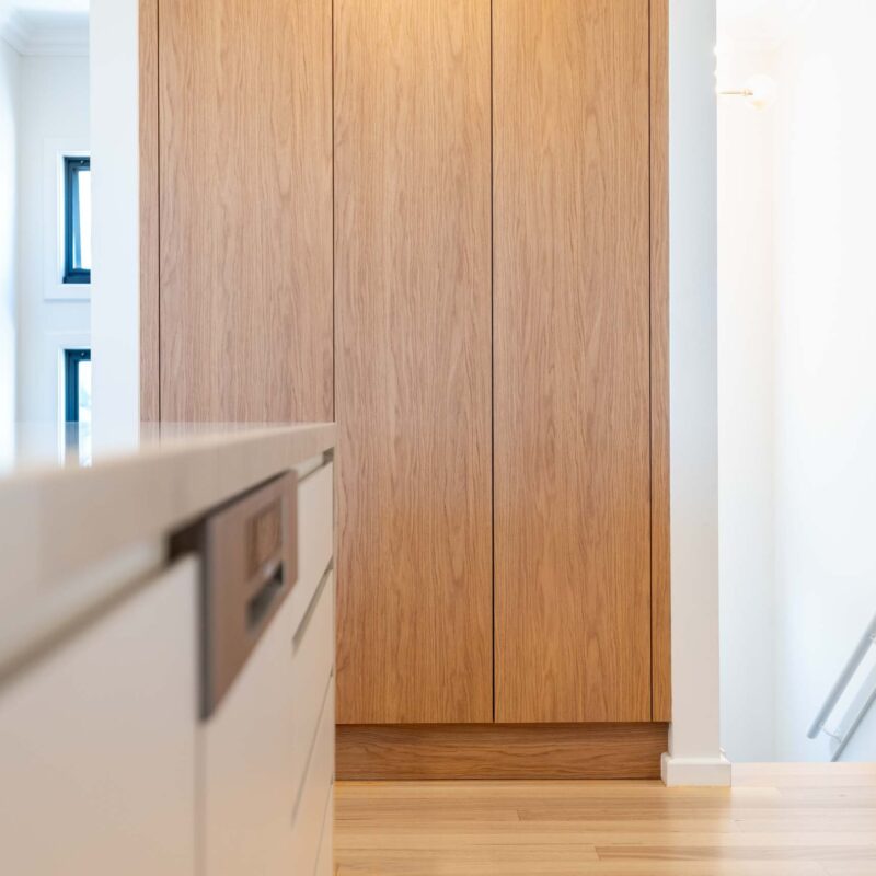 Floor to ceiling oak timber look laminate storage cabinets.