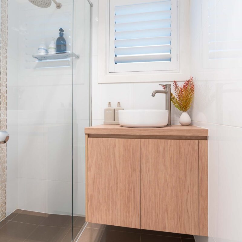 Timber laminate bathroom double door floating vanity. White top mount sink with brushed chrome mixer tap.