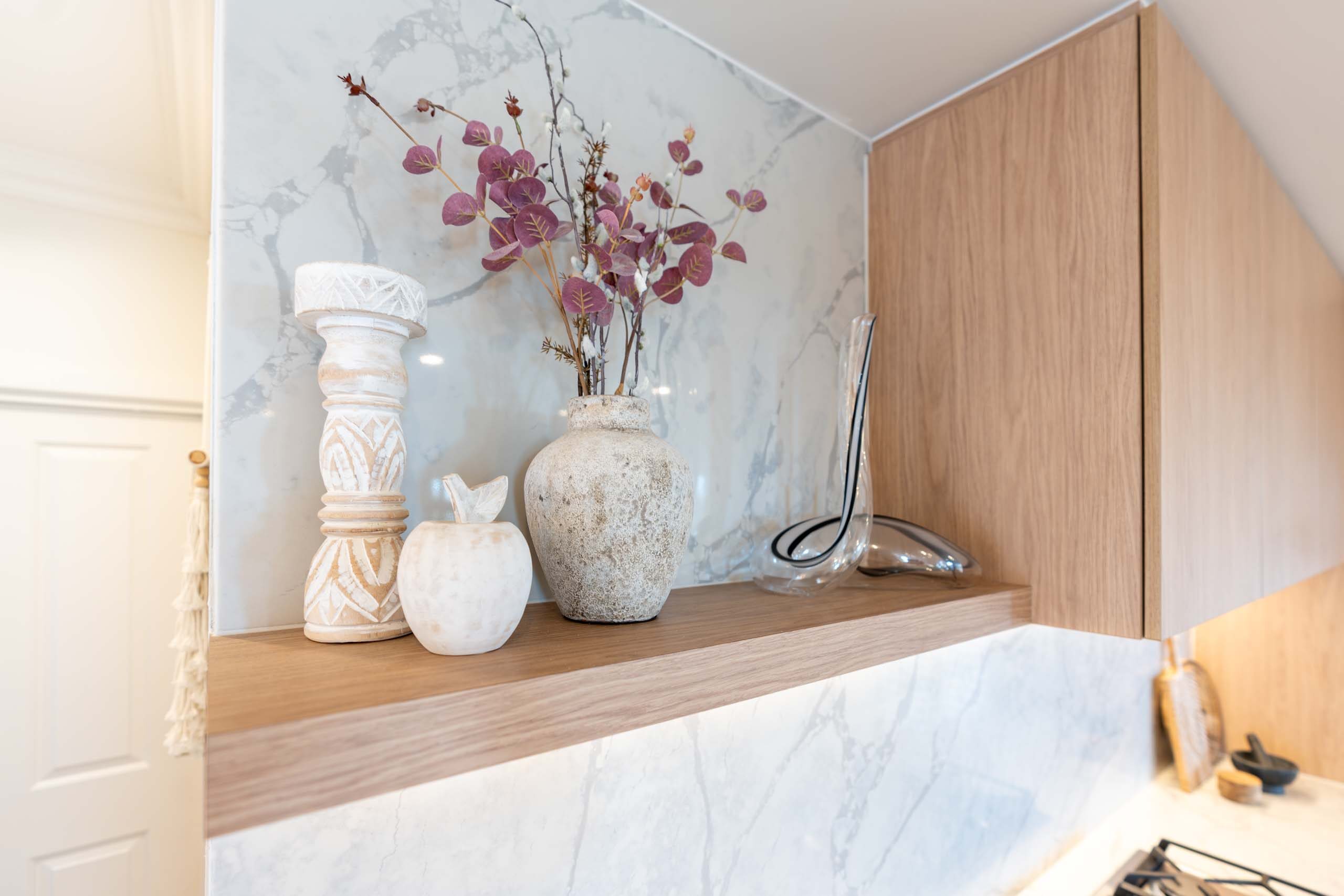 Oak timber-look floating shelf positioned next to a integrated rangehood cabinet.