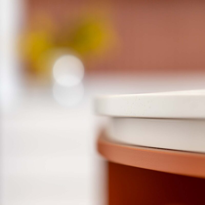 White curved edge benchtop shadowing an orange curved open shelf cabinet.