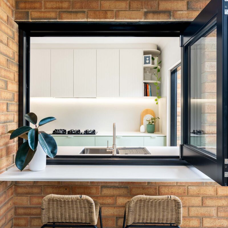 Bi fold kitchen window that opens up to outdoor alfresco seating. Featuring engineered stone benchtops.