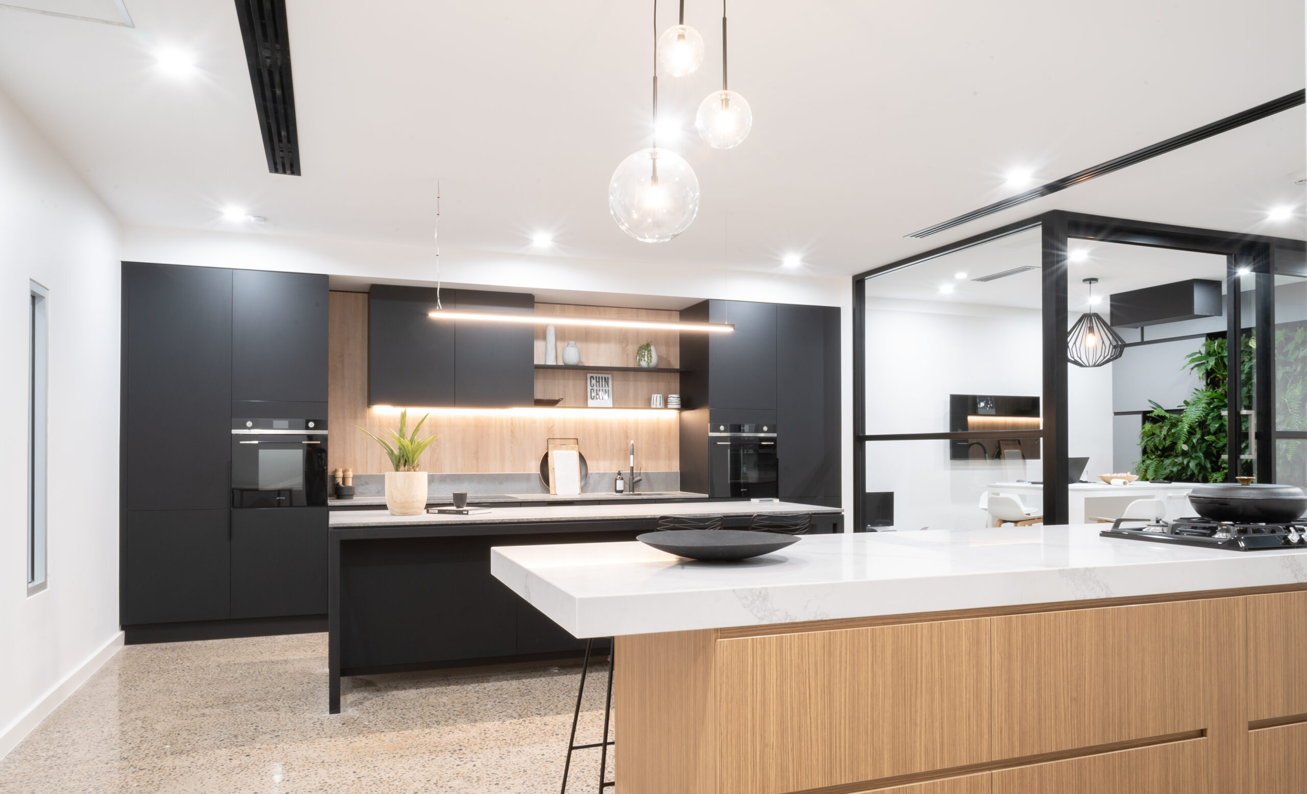Sleek and industrial kitchen display at the Marion Road Farquhar showroom. Featuring our matte black anti-fingerprint cabinets and 12mm Dekton benchtops in Kovik.
