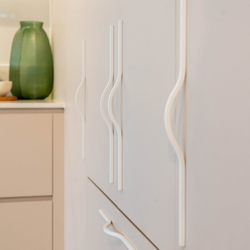 Integrated fridge hidden behind laminate Coolum sand doors featuring large slimline white handles.