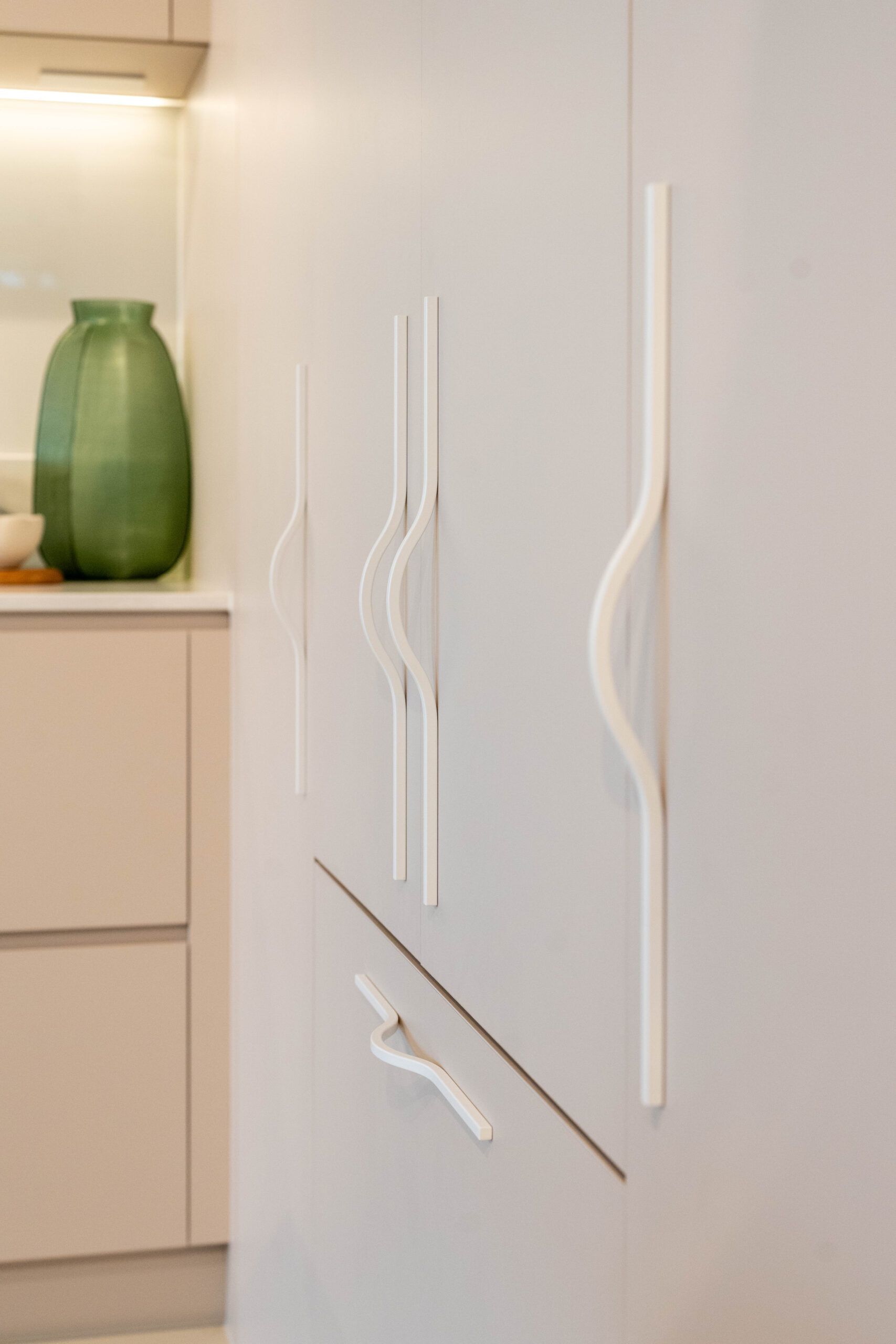 Integrated fridge hidden behind laminate Coolum sand doors featuring large slimline white handles.