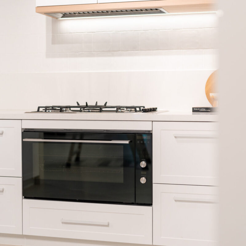 Classic Hampton style kitchen featuring shaker style cabinets, a white engineered stone and timber features.