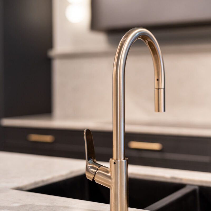Light coloured solid surface bench top featuring a black under mount sink and brushed stainless steel goose neck mixer tap.