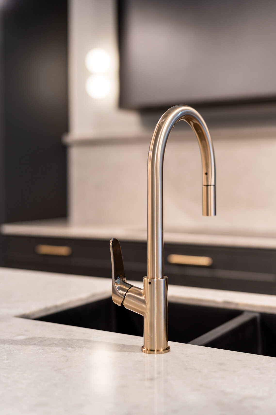 Light coloured solid surface bench top featuring a black under mount sink and brushed stainless steel goose neck mixer tap.