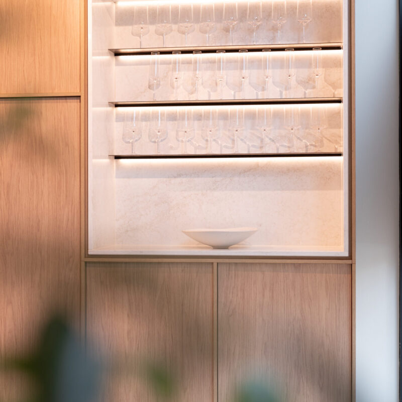 Light woodgrain kitchen featuring a glass open shelf cabinet with LED feature strip lighting.