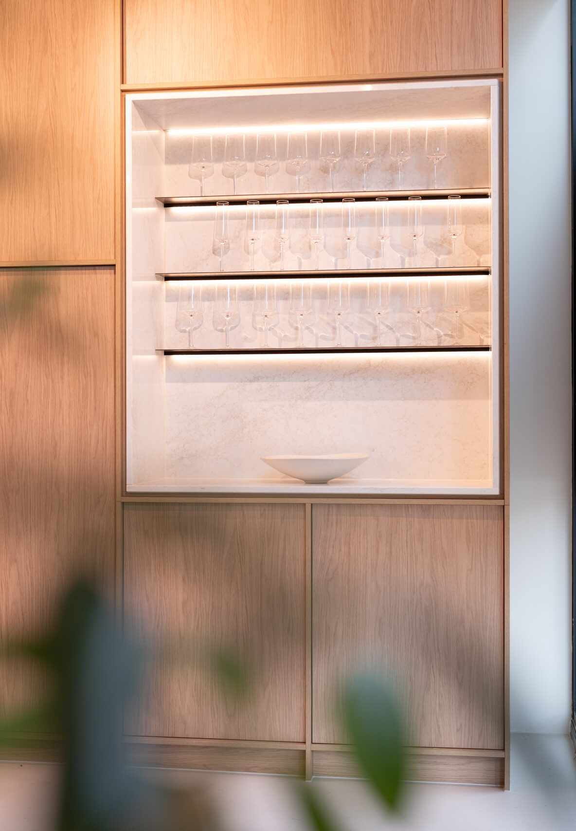 Light woodgrain kitchen featuring a glass open shelf cabinet with LED feature strip lighting.