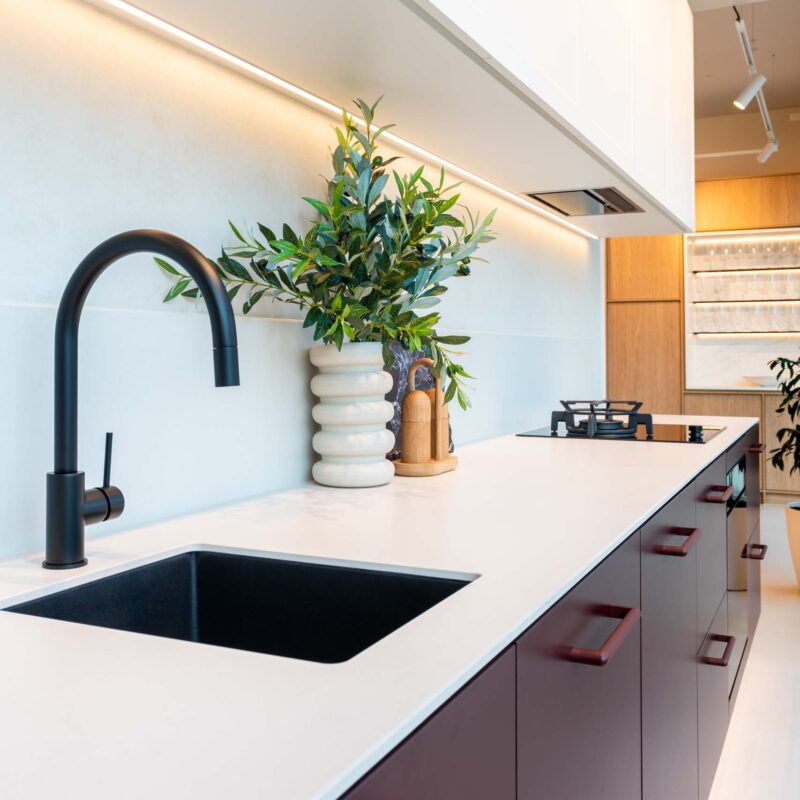 Small kitchen with Kalamata laminate cabinets and a light 12mm Dekton Aeris benchtop. Featuring a matt black goose neck mixer tap and under mount sink.