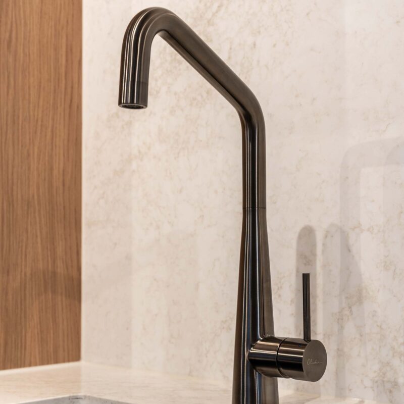 Gun Metal goose neck mixer tap with an under mount sink. Solid surface splash back.
