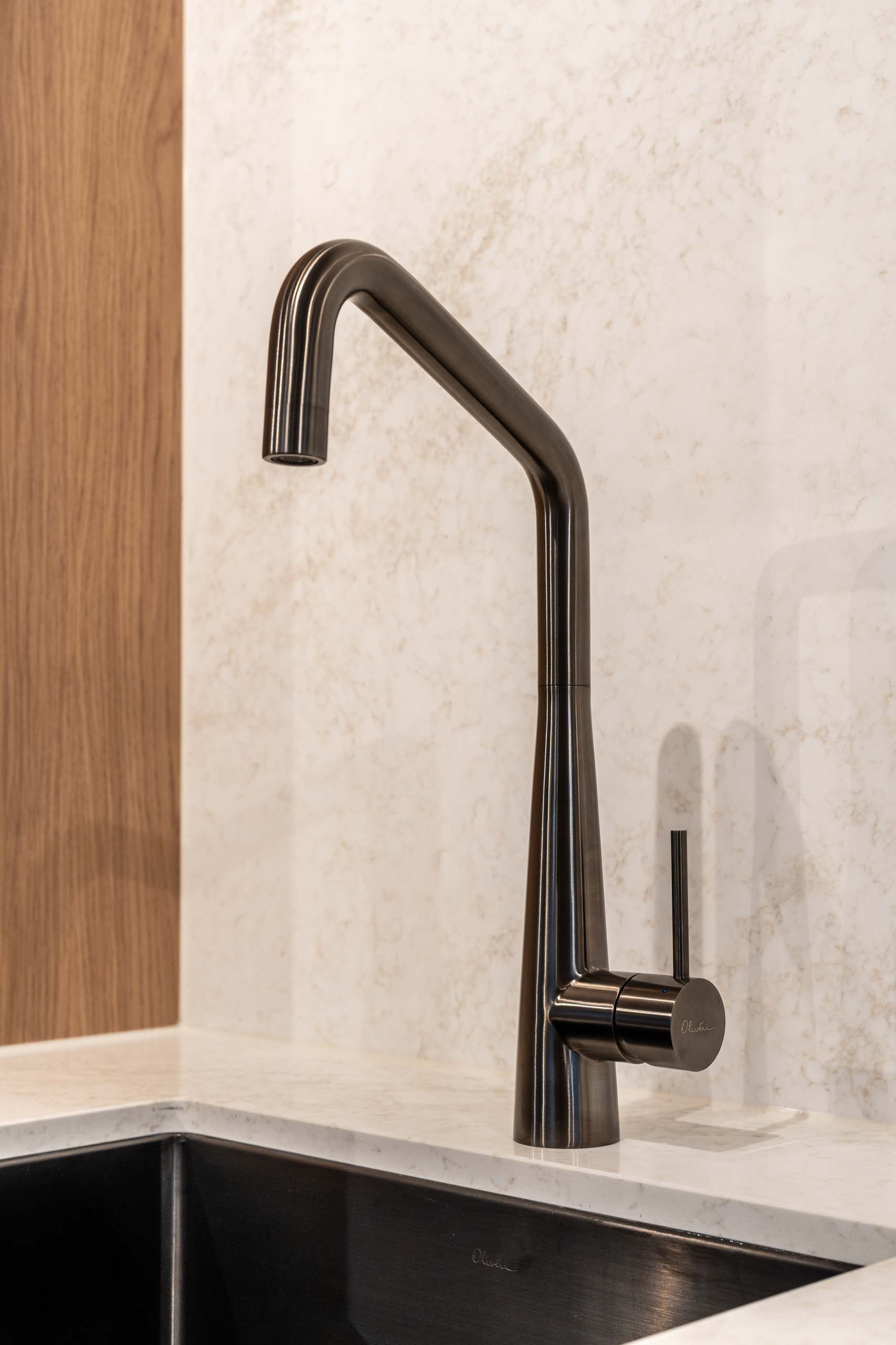 Gun Metal goose neck mixer tap with an under mount sink. Solid surface splash back.